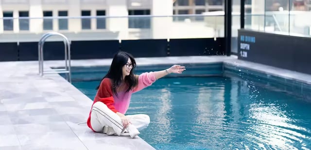 Woman by swimming pool with depth marker playing area at Scape Aurora in Melbourne Student Accommodation