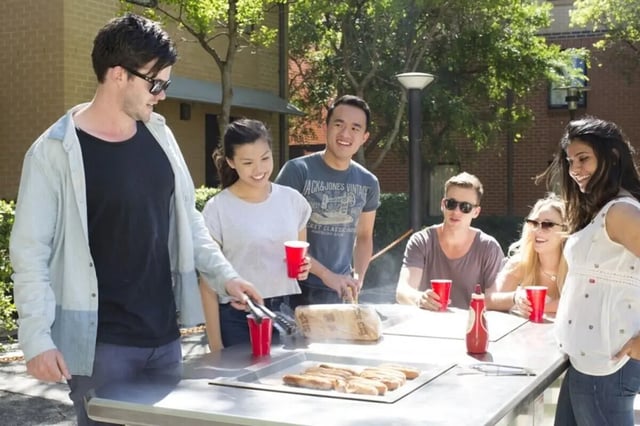 Students grilling sausages at outdoor table exterior at Sydney University Village in Sydney Student Accommodation