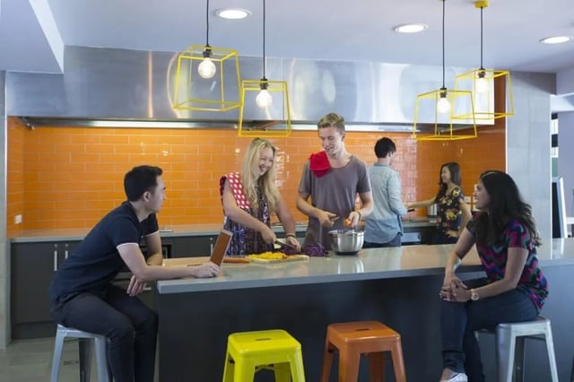 Students cooking and sitting at kitchen counter kitchen at Sydney University Village in Sydney Student Accommodation