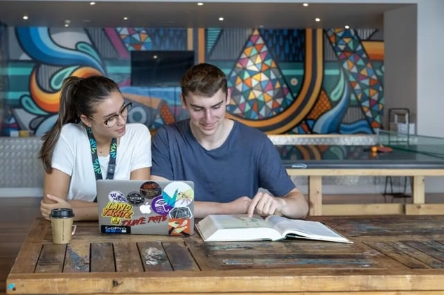 Students studying at table with laptop and book Common area at Sydney University Village in Sydney Student Accommodation
