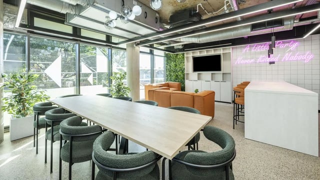 Long table green chairs orange sofa neon sign communal area at The Printworks in Exeter Student Accommodation