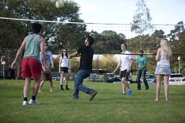 Students playing volleyball on a grassy court outdoors playing area at Student Village North Ryde in Sydney Student Accommodation