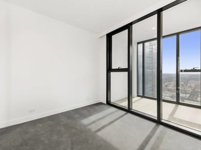Empty white room with grey carpet and windows bedroom at Belong Melbourne CBD in Melbourne Student Accommodation