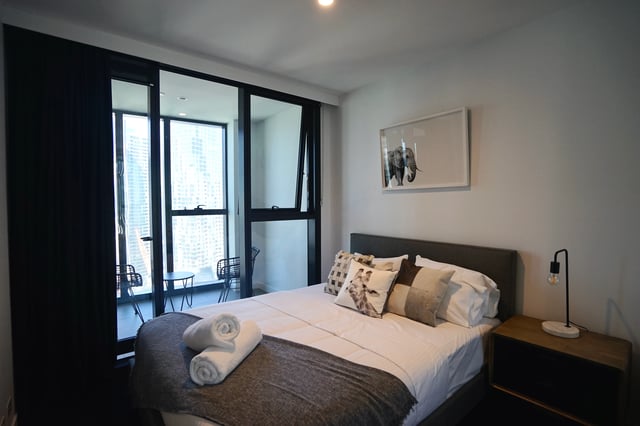 Bed with rolled towels and elephant art Bedroom at Belong Melbourne CBD in Melbourne Student Accommodation