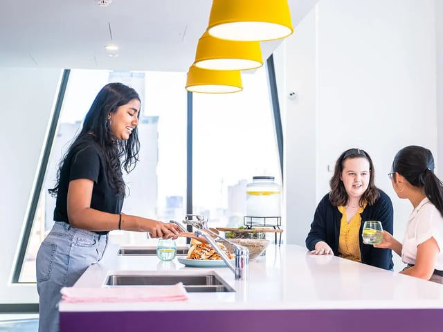 Students preparing food and talking in kitchen at Yugo Adelaide City in Adelaide Student Accommodation