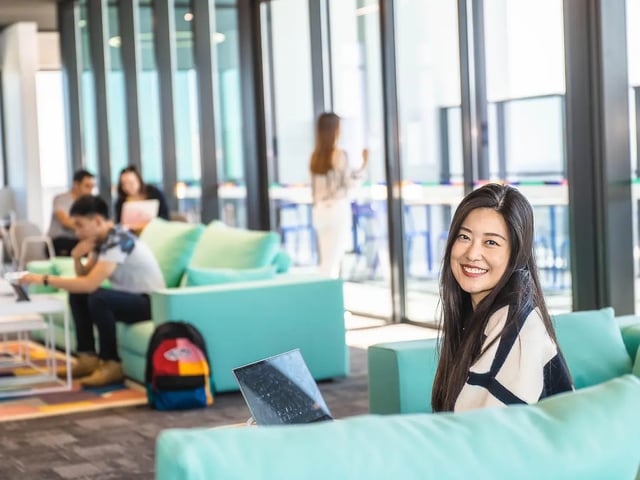 Young woman smiling in a modern lounge living room at Yugo Adelaide City in Adelaide Student Accommodation