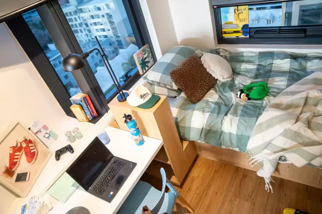 Bed laptop desk and city view bedroom at Scape Carlton in Melbourne Student Accommodation