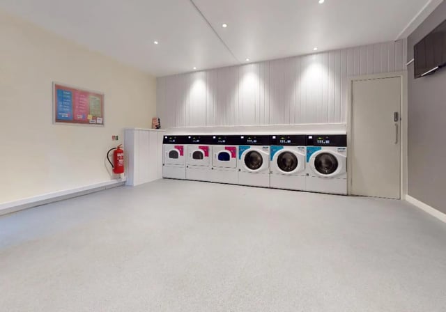 Row of washing machines fire extinguisher notice board laundry room at iQ Newland House in Nottingham Student Accommodation