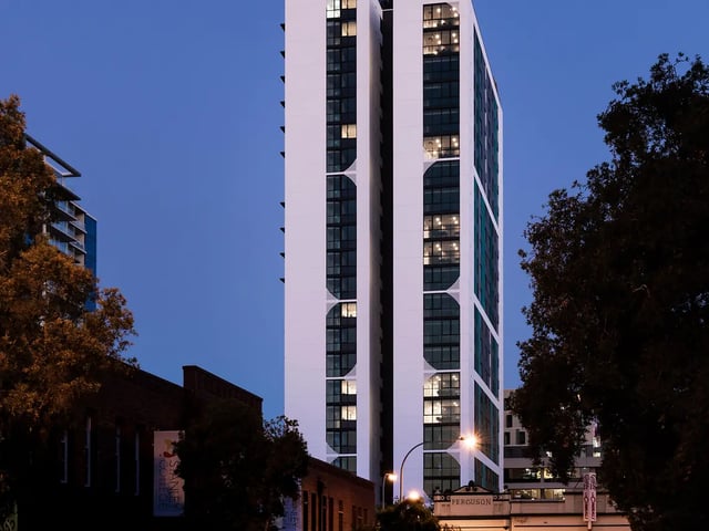 Modern high rise building with lit windows exterior at Yugo Perth City in Perth Student Accommodation