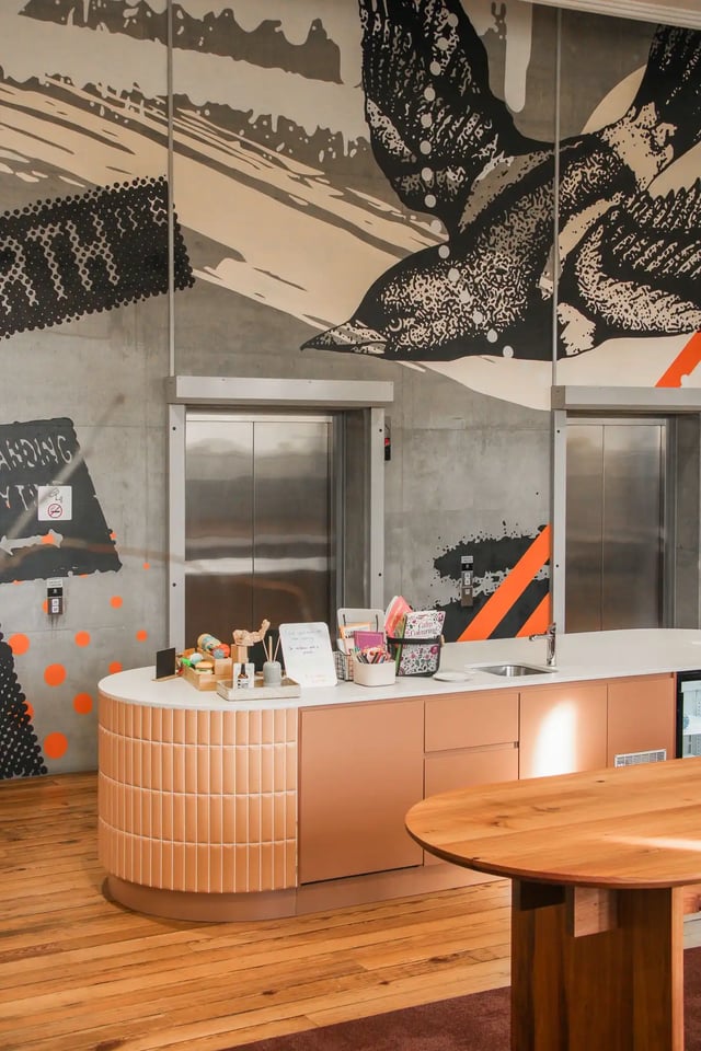 Elevator bank with counter and colorful mural living room at The Switch Adelaide in Adelaide Student Accommodation