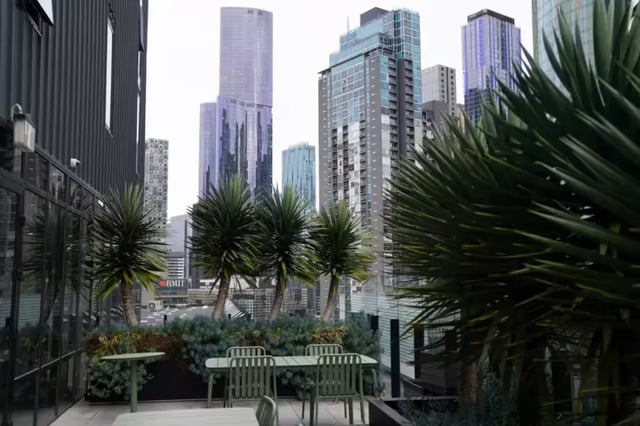 Tables chairs plants with cityscape exterior at Scape Cornell Place in Melbourne Student Accommodation