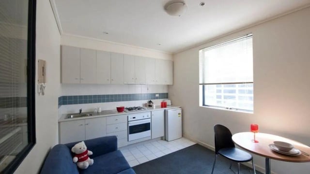 Blue sofa stove sink fridge table kitchen at Student Living On ABeckett in Melbourne Student Accommodation