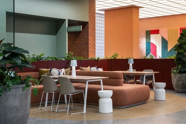 Orange sofas tables chairs lamps plants art living room at Campus House in Melbourne Student Accommodation