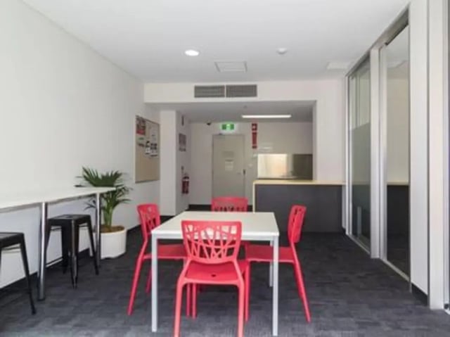 Table with red chairs and desks communal area at UniLodge @ Metro Adelaide in Adelaide Student Accommodation