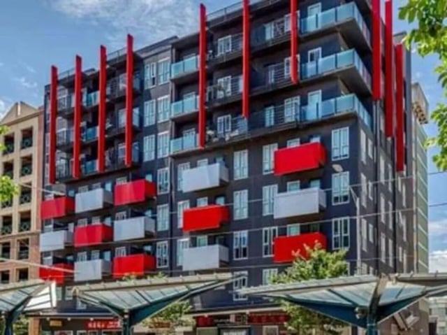 Modern apartment building red balconies blue glass exterior at Student Living - 740 Swanston in Melbourne Student Accommodation