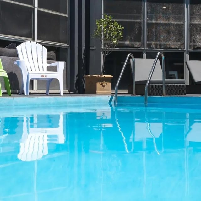 White chairs by blue swimming pool exterior at Sydney Student Living Concord in Sydney Student Accommodation