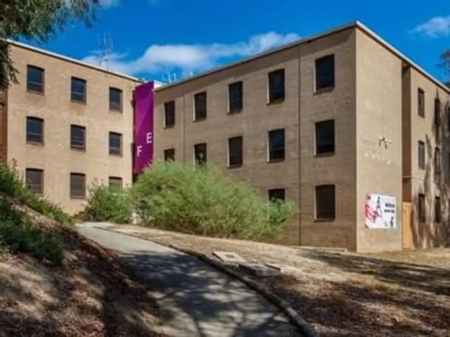Brick building with purple banner and posters exterior at UniLodge @ UC - Campus West & Guginya in Canberra Student Accommodation