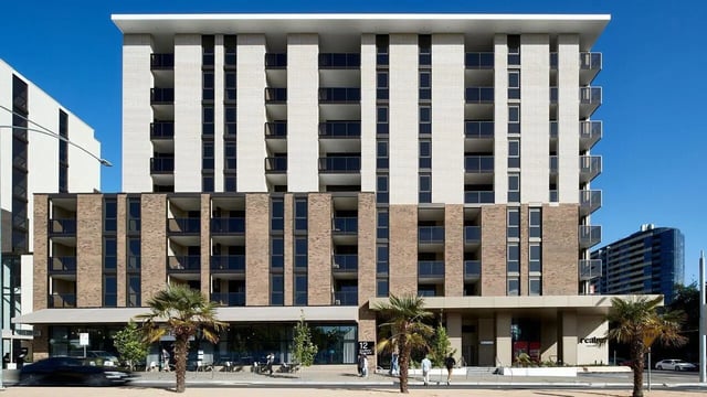 Modern apartment building with balconies and palm trees exterior at Realm Caulfield in Melbourne Student Accommodation