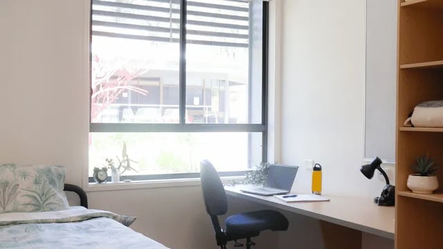 Bed desk with laptop and chair bedroom at La Trobe University - Hillside Apartments in Melbourne Student Accommodation