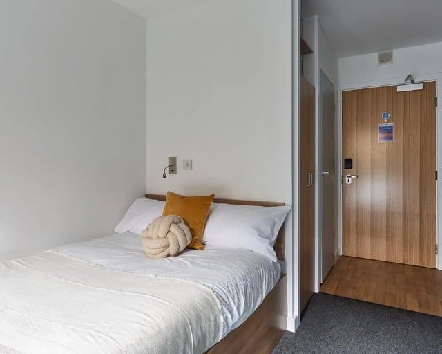 Bed with white linens door and closet bedroom at Cavendish Place in Manchester Student Accommodation