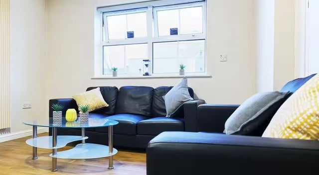 Black couches glass coffee table potted plants living room at Oxney House & Gardens in Manchester Student Accommodation