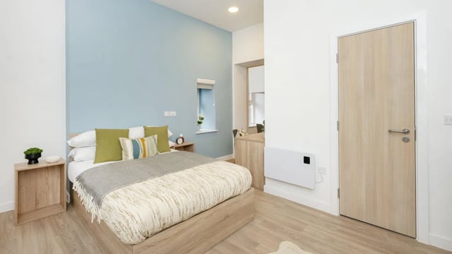 Bed with pillows side table and door bedroom at Westcombe House in London Student Accommodation