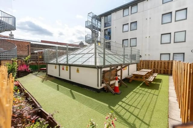 Picnic tables and planters on artificial turf exterior at Don Gratton House in London Student Accommodation