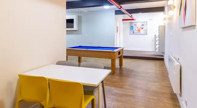 White table yellow chairs pool table common area at Nottingham Square in Nottingham Student Accommodation