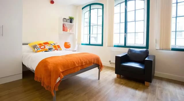 Bed with orange throw armchair and windows bedroom at Nottingham Square in Nottingham Student Accommodation