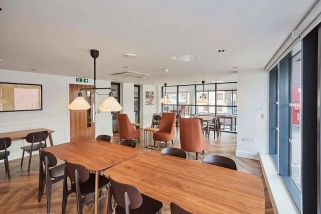 Wooden tables chairs and orange armchairs living room at Mannequin House in London Student Accommodation