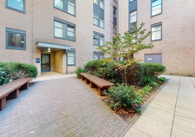 Brick building with benches and green landscaping Exterior at iQ Tufnell House in London Student Accommodation