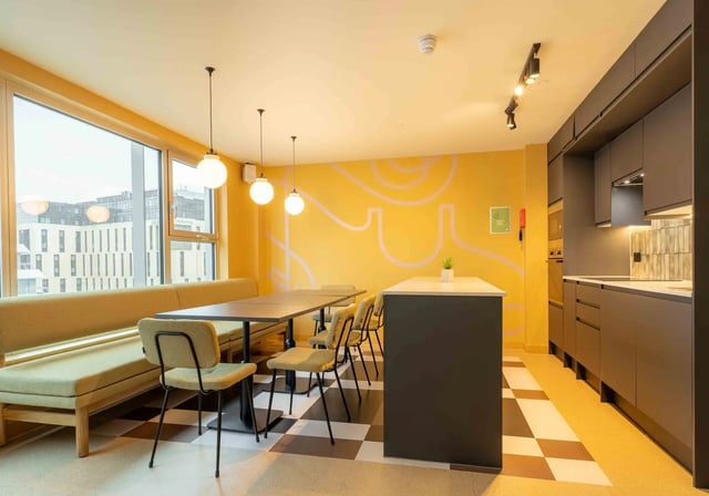 Kitchen with island seating and dining area at iQ Paris Gardens in London Student Accommodation