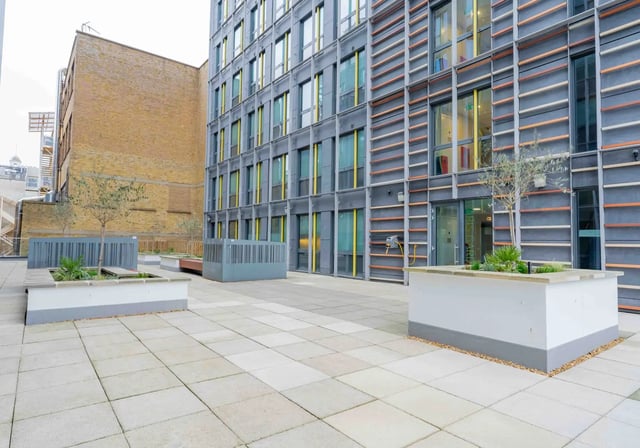 Paved outdoor area with planters and modern building exterior at iQ Paris Gardens in London Student Accommodation