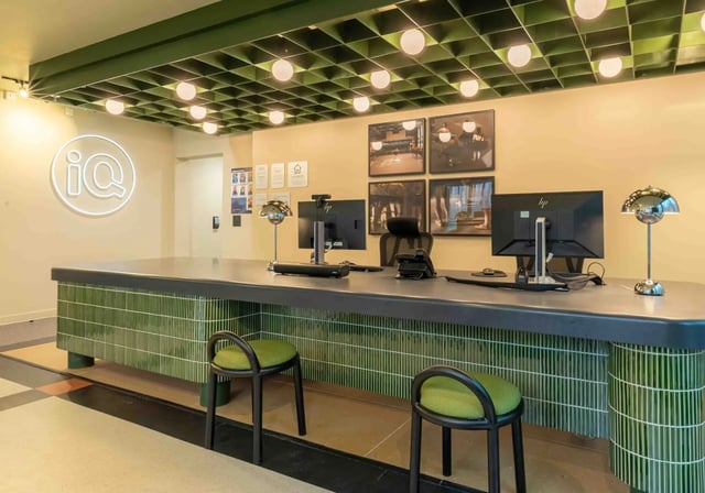 IQ logo reception desk with computers and stools reception area at iQ Paris Gardens in London Student Accommodation