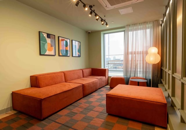 Orange sectional sofa abstract art and ottoman living room at iQ Paris Gardens in London Student Accommodation