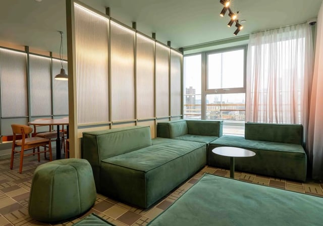 Green sectional sofas with ottoman and table Living room at iQ Paris Gardens in London Student Accommodation