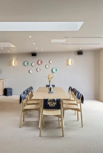 Wooden dining table with chairs and wall plates communal dining area at ARK Wembley in London Student Accommodation