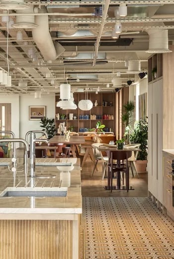 Kitchen island sink shelves with books tables chairs living area at ARK Wembley in London Student Accommodation