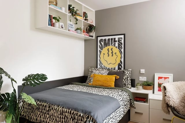 Bed with patterned duvet yellow pillow Smile poster bedroom at Houghall Court in Durham Student Accommodation