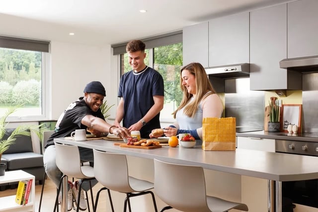 Students eating breakfast at kitchen island kitchen at Houghall Court in Durham Student Accommodation