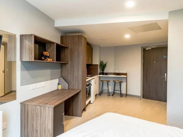 Desk shelves kitchen with stools and door studio apartment at Scotway House in Glasgow Student Accommodation