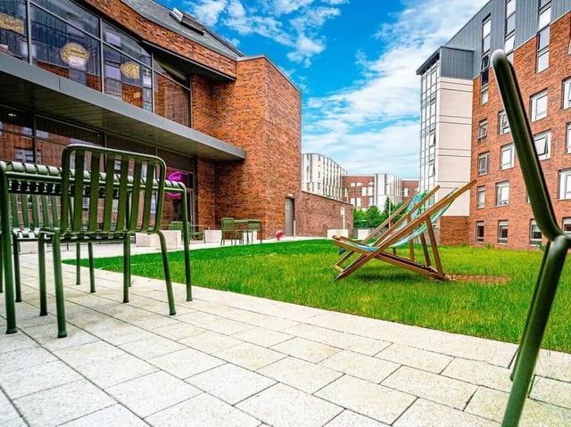 Green chairs lounge chairs and brick buildings exterior at Scotway House in Glasgow Student Accommodation