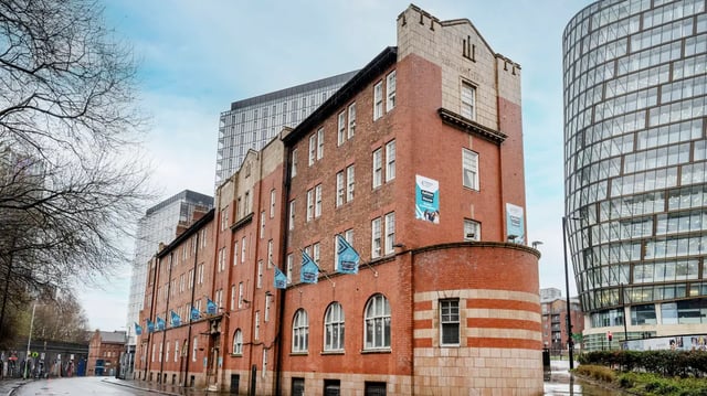 Brick building with flags and modern skyscraper exterior at Ashton House in Manchester Student Accommodation