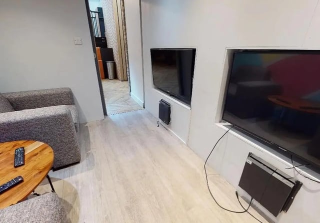 Grey sofa coffee table with remotes and TVs living room at iQ Kerria Apartments in Manchester Student Accommodation