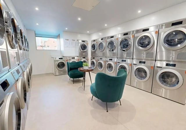 Washing machines and dryers with seating area laundry room at iQ Wilmslow Park in Manchester Student Accommodation