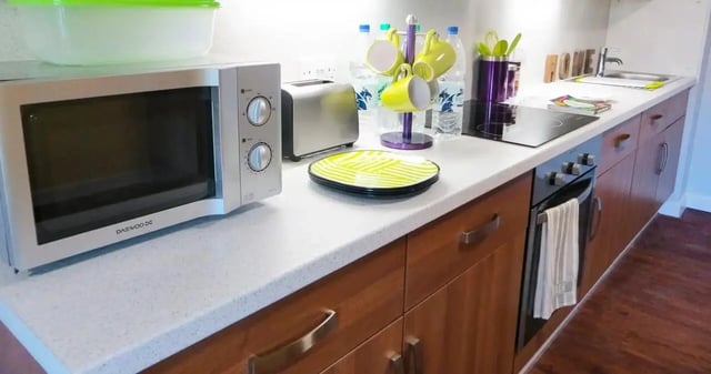 Microwave toaster mugs plates sink stove kitchen at Kaplan Living Nottingham in Nottingham Student Accommodation