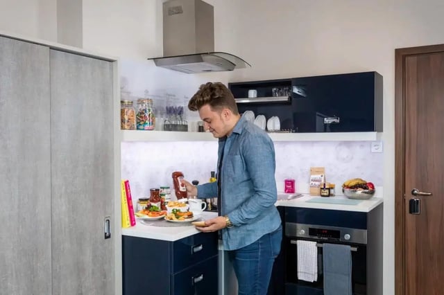 Man preparing food in modern student kitchen kitchen at Triumph House in Nottingham Student Accommodation