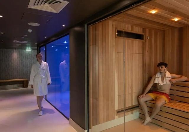 People in robes and a man in a sauna living area at Triumph House in Nottingham Student Accommodation