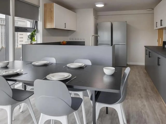 Dining table with place settings and kitchen area kitchen at Yugo Goldsmith Court in Nottingham Student Accommodation