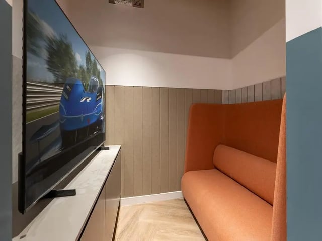 TV on cabinet next to orange sofa living room at Fabric in Nottingham Student Accommodation